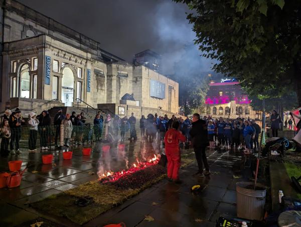 Firewalkers prepare to walk the hot coals in front of Leeds Art Gallery. Spectators are gathered 