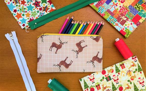 A rectangle pencil case with colourful pencils surrounded by christmas fabric and zips