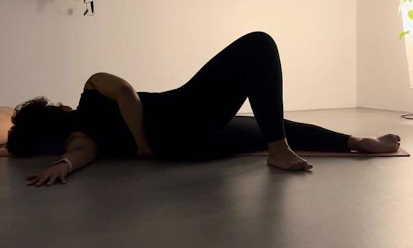 Yoga teacher Sarah lying down in a Yoga pose called Broken Wing