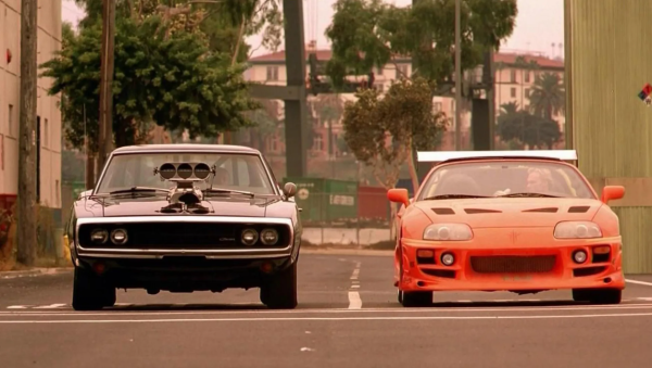 A black and an red car line up for a drag race 