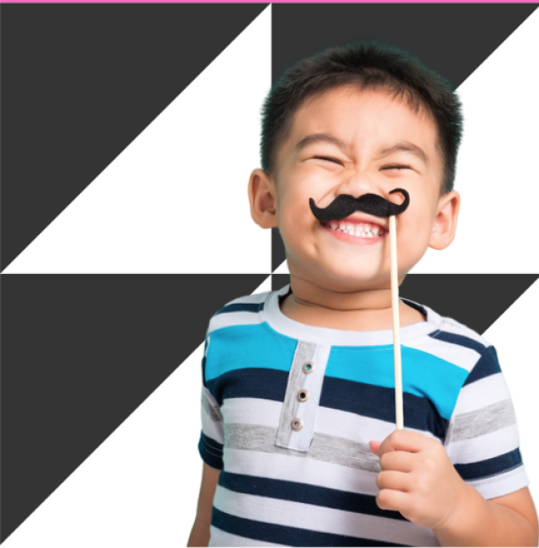 A child holding up a paper moustache on stick to his face on a black and white background