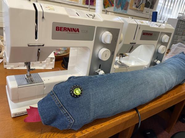 denim snake lying alongside a sewing machine