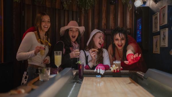 A group of people playing shuffleboard at Electric Shuffle, all while dressed in Halloween outfits.