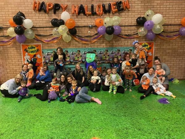 Photo showing lots of families dressed up in Halloween costumes with balloons and decorations