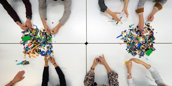 adult arms reaching for piles of LEGO