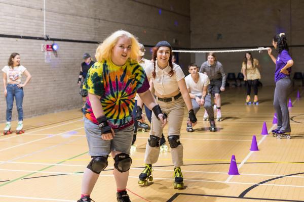 Roller skaters skating on a darkened sports hall 