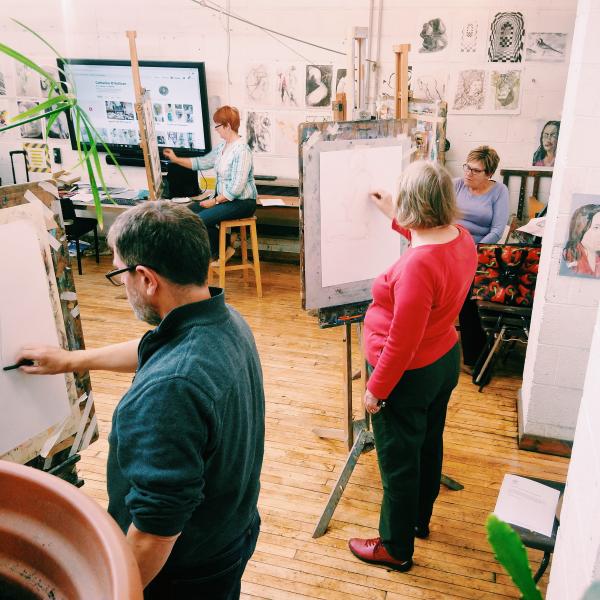 a man and a woman stood up at an easel beginning a life drawing