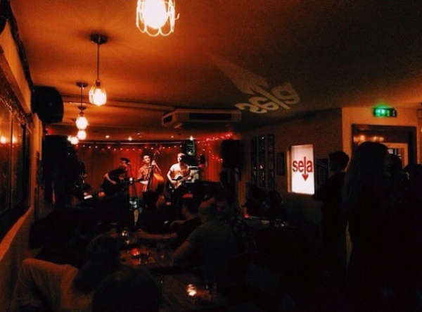 A red lit basement room with band playing on stage.