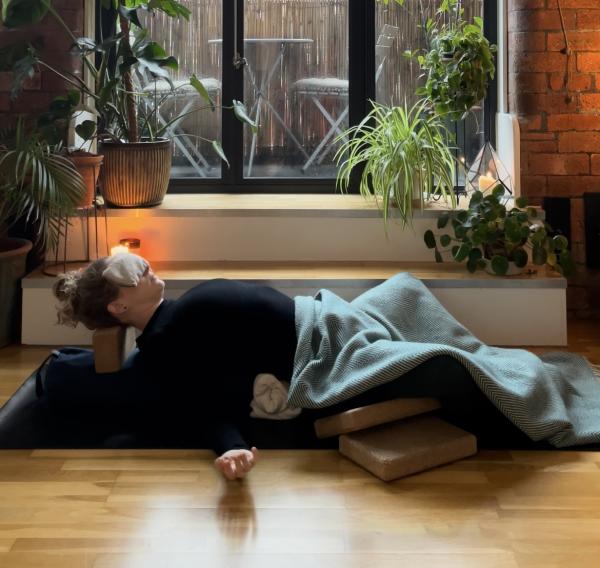 Anna Louise Hardy laying in a restorative position surrounded by candles.