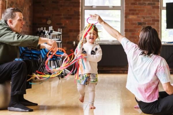 A toddler runs through colourful ribbons