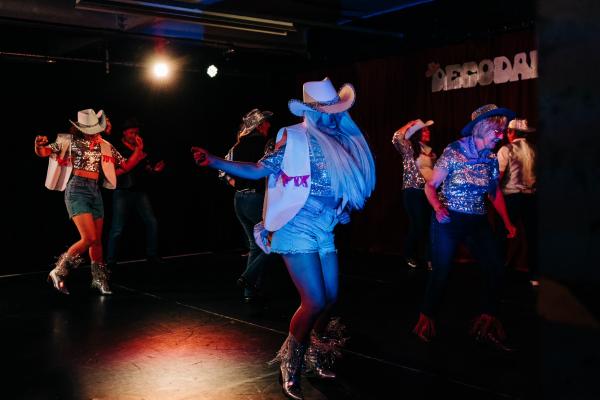 Image of dancers smiling in cowboy hats and boots.