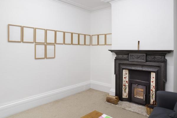 Row of artworks on a wall and a fireplace on an adjacent wall