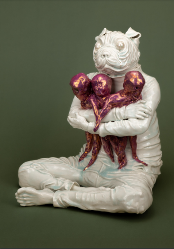 Seated ceramic figure with a dog head holding three small, metallic purple human-like forms against a muted green background