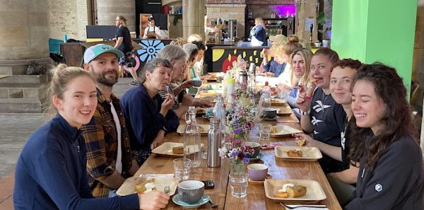 Photo of Yoga Brunch community sat around a long table enjoying a communal brunch at a past a past event.