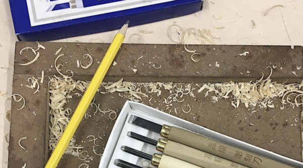 A selection of woodcutting tools with a pencil, surrounded by wood shavings