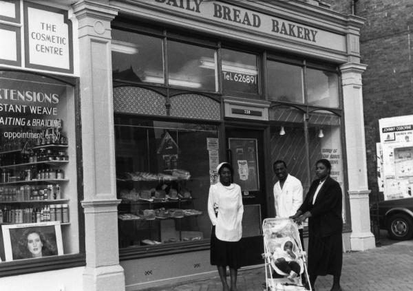 Black and white photograph of a family stood outside a shop