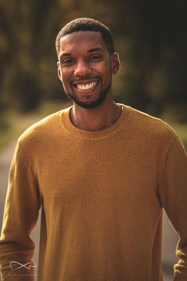 Photographic portrait of author Ashley Thorpe wearing an orange jumper.