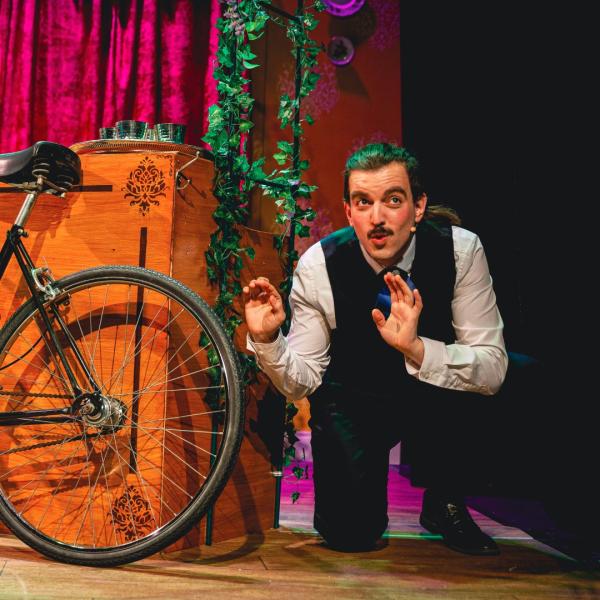 Man crouched next to a wooden box where a bicycle is leaning against.