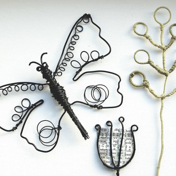 A trio of wire sculptures, one butterfly made from thin black wire, and two flowers