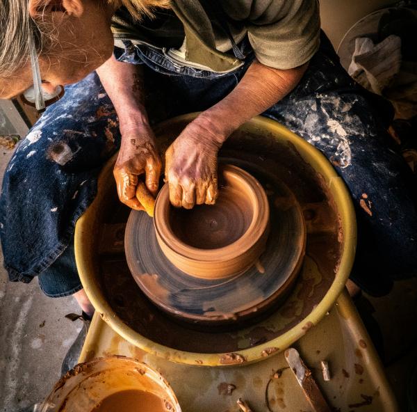 A lady at a pottery wheel making a ceramic pot