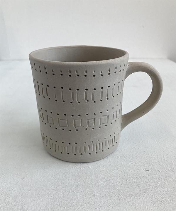 Handmade clay mug with surface texture and design. The mug has been made using handbuilding / slab building methods