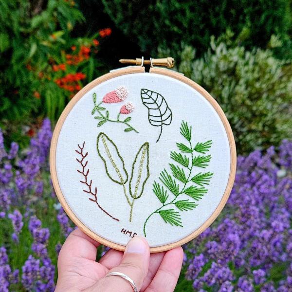 Hand holding embroidery hoops with embroidered flowers 