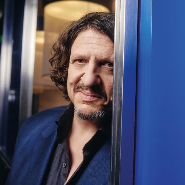 Jay Rayner peeking through a metal door with part of the left side of his face obscured.