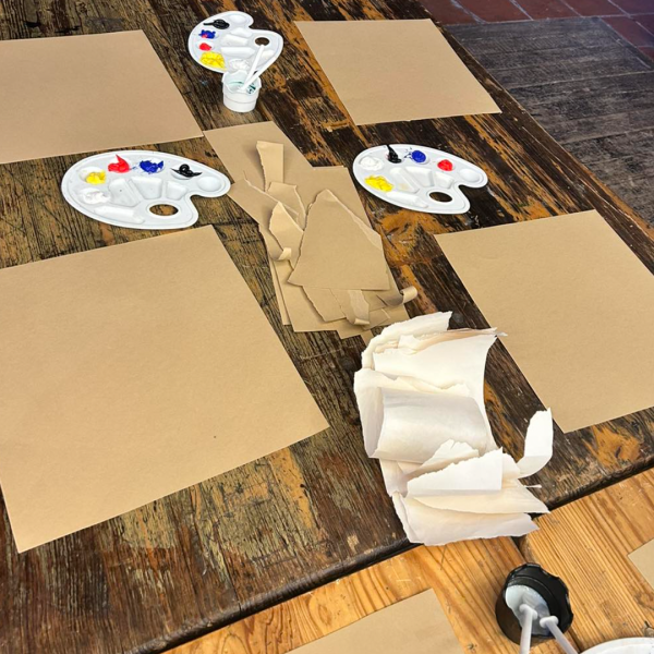 A table set up for a kid's art workshop with paper and paint palettes