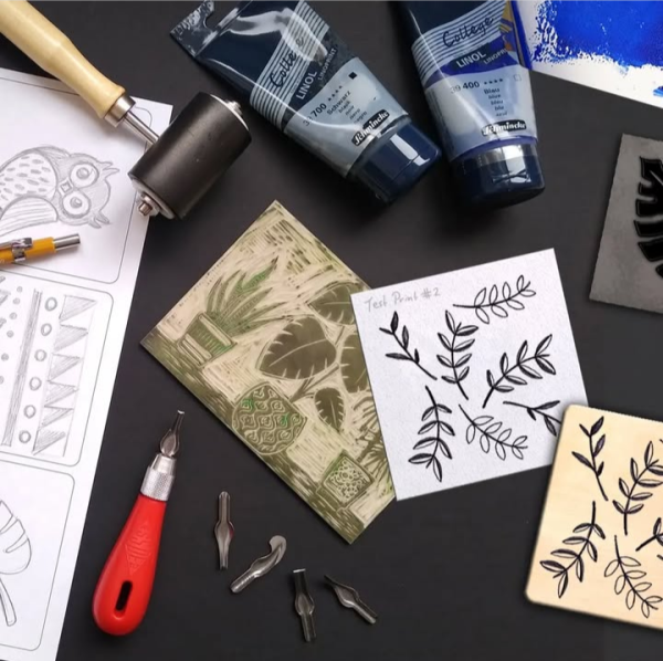 Image of lino printing materials, cut lino sheet featuring plants, roller and inks.