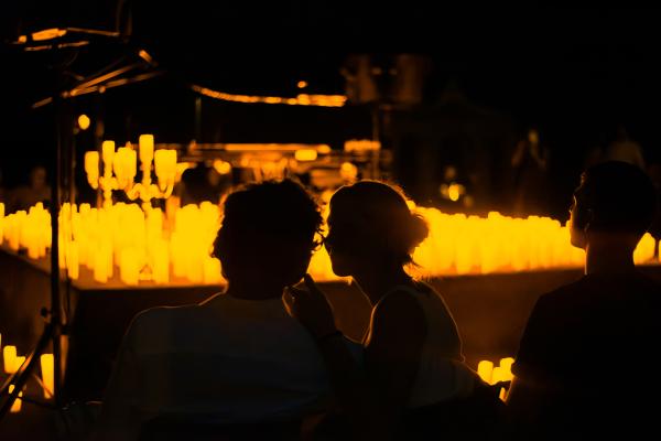 A room with candles where a couple watches a classical concert