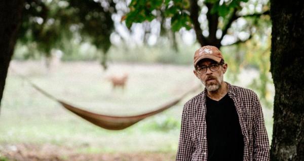 A man stood in front of a hammock.