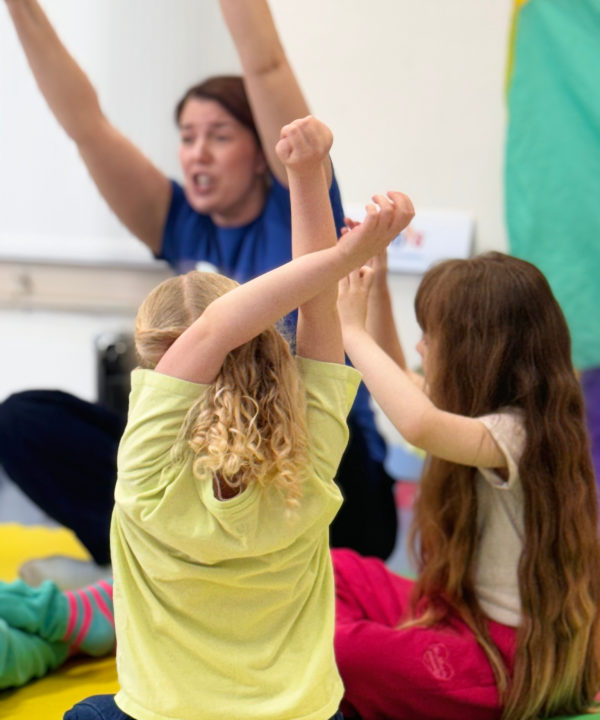 Two children and an adult reaching high during a story time