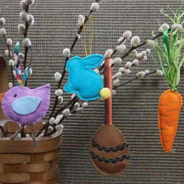 a felt chick, bunny, egg and carrot dangle from a branch