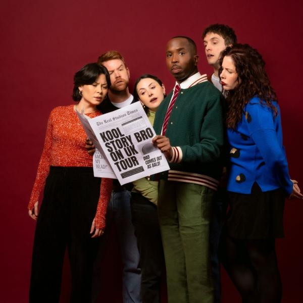 Kiell-Smith Bynoe holding a newspaper with the front page headline that reads Kool Story Bro on UK Tour. He is surrounded by other comedians including Emma Sidi, Lola-Rose Maxwell, Nic Sampson, Graham Dickson and Anna Leong Brophy trying to get a peek at the newspaper or staring at Kiell.