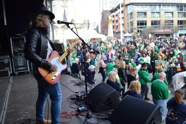 Performer on stage, with electric guitar, and audience. 