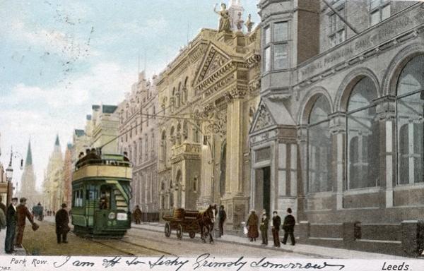 An image of Park Row in Leeds (1903) with a tram going past elegant Victorian buildings.