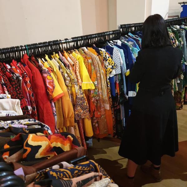 A woman shopping through a rail of 60s and 70s vintage dresses