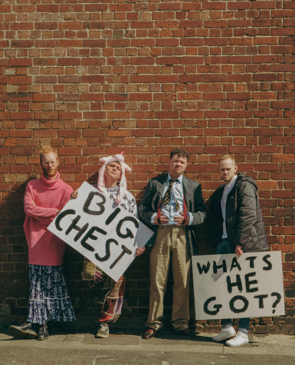 Four mean in various dress standing against a brick wall