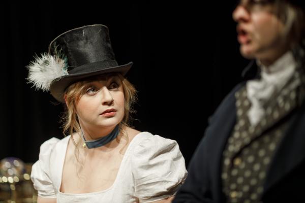 An actor wearing a top hat with a feather in it.