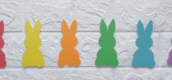 A row of cardboard bunny silhouettes in yellow, orange, green, turquoise, purple and red.