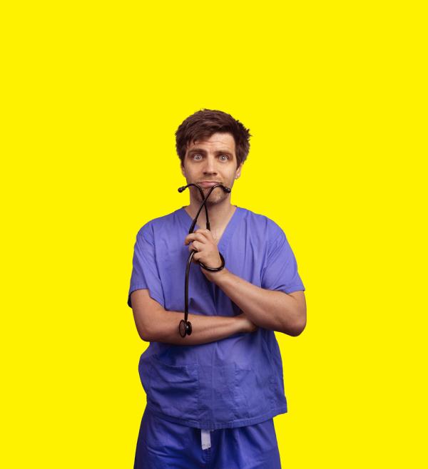 Ed Patrick wearing scrubs holding a stethoscope in front of a yellow background.