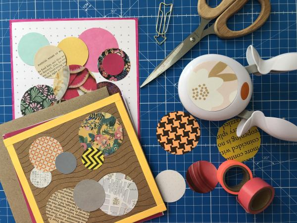 Two greetings cards covered in paper collage dots with adjacent scissors and coloured washi tape.