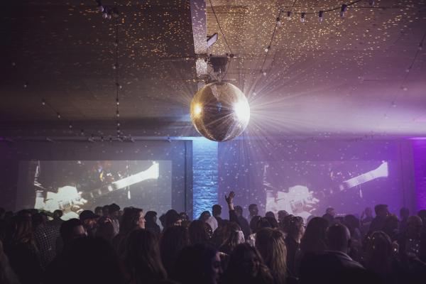 Disco ball and projections on a wall in a busy club.