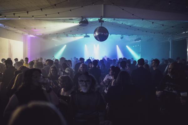 Image of a room full of people dancing near a stage.