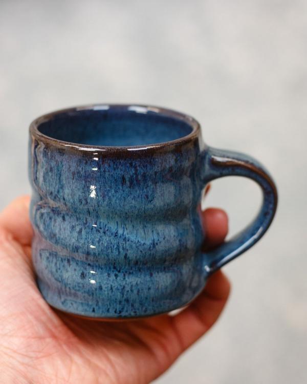A Blue wheel thrown ceramic mug, with a glossy glaze and swirl design