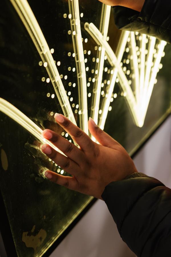 A hand touches a lightbox with firework-like design on