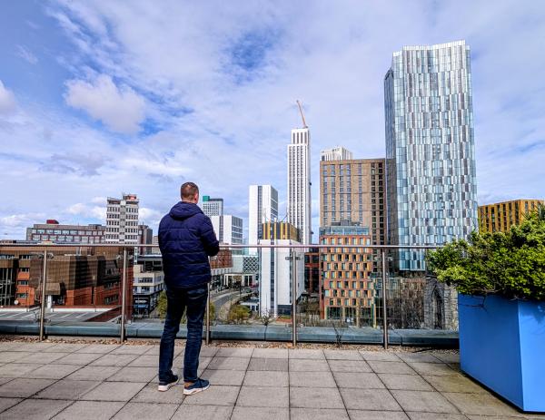 A person stansding on a rooftop terrace looking at the Leeds City Centre skyline