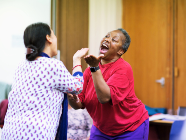 2 people are dancing smiling and gesturing toward each other