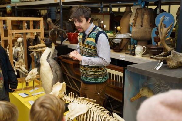 Man giving a tour of the store room, surrounded by taxidermy