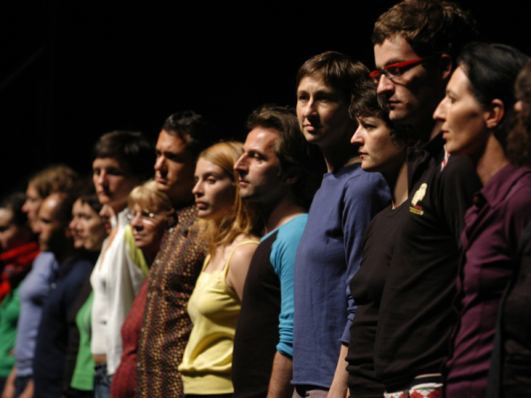 People in colourful t-shirts stand in a line looking serious 